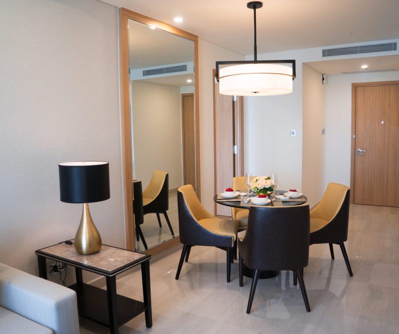 Dining area of comfortable studio flat or hotel room. Set dining table prepared for dinner with Asian cuisine. City apartment and interior concept